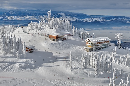 Panoramic view over the ski slope Poiana Brasov ski resort in Transylvania, Pine forest covered in snow on winter season,Mountain landscape in winter @ credit Depositphotos