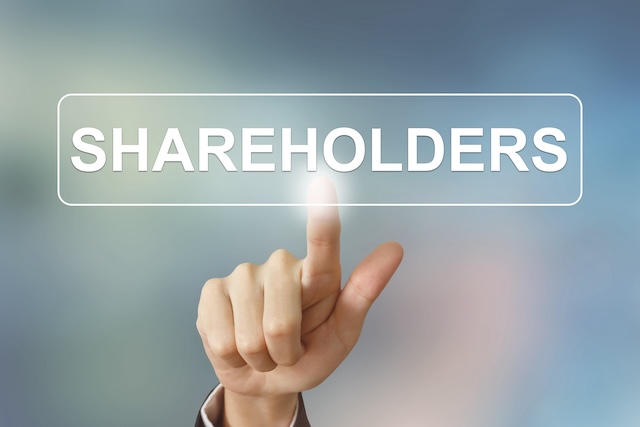 business hand pushing shareholders button on blurred background