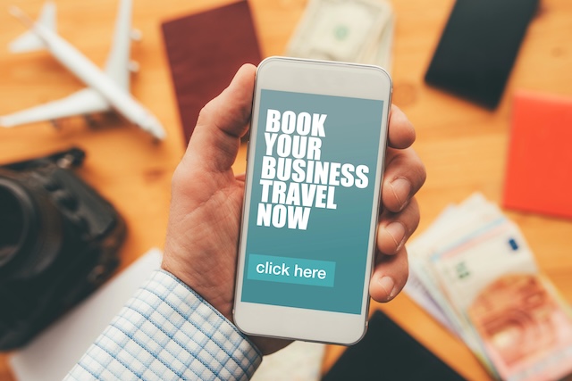 Book your business travel now online mobile app. Man holding smartphone with mock up application screen related to holiday vacation journey trip