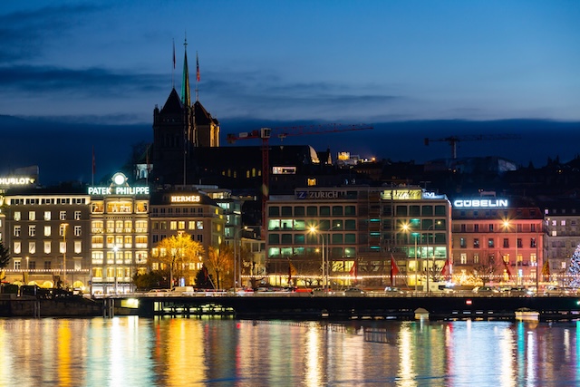 GENEVA, SWITZERLAND - DECEMBER 30, 2021: Scenic night view of illuminated modern Geneva cityscape as seen from lake in winter