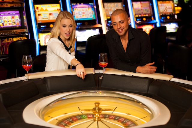 Young couple playing roulette in casino betting and winning