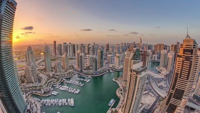 Sunrise over Dubai Marina skyscrapers and jumeirah lake towers panoramic view from the top aerial morning timelapse in the United Arab Emirates. Floating yachts and boats