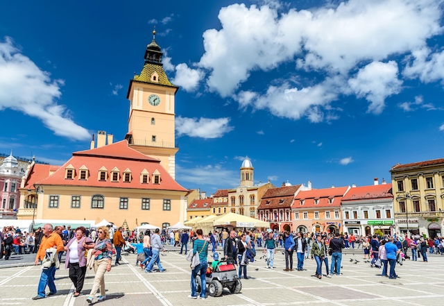 BRASOV, ROMANIA - 27 APRIL 2014: Scenery with tourists walking in Main Square, landmark with Council House in medieval center of Brasov, Transylvania, Romania.