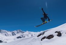 ❄️ Global Sustainability Ski Alliance | Les géants du ski s’unissent pour des montagnes durables Young female skier jumping from ski jump on sunny day in snowy alpine mountains, moment in flight.