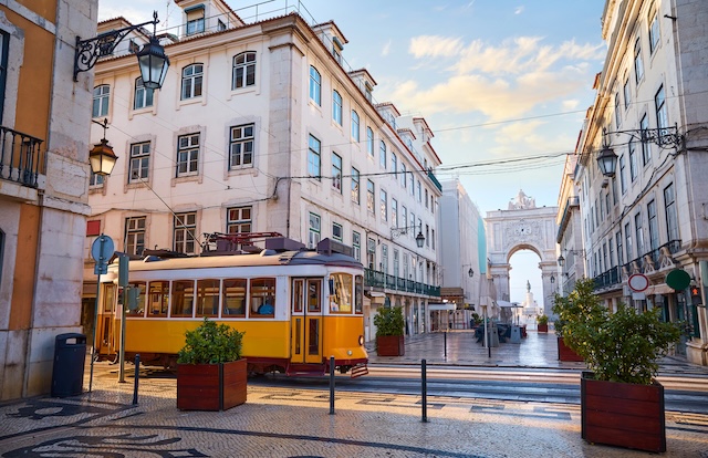 Lisbon, Portugal. Yellow touristic retro tram. Triumphal Arch of Rua Augusta near Praca do Comercio (Commercial Square. Sunny day in famous tourist place Lisboa