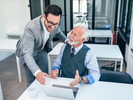 Débat | L’avenir des directions hôtelières passe-t-il par le leadership intergénérationnel ? Senior boss happy for good online work result of young male businessman.