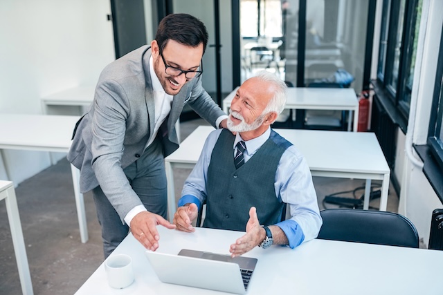 Senior boss happy for good online work result of young male businessman.