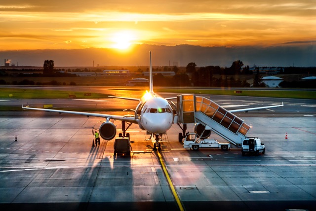 Airplane near the terminal in an airport at the sunset @ credit Depositphotos