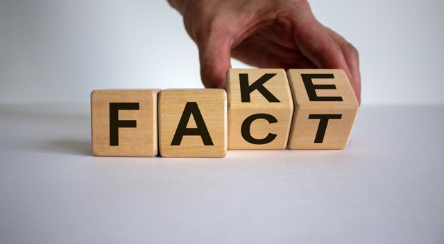 Business and design concept. Man hand flips wooden cubes with words 'FACT FAKE' concept on beautiful white background, copy space.