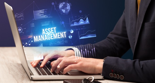 Businessman working on laptop with ASSET MANAGEMENT inscription, new business concept